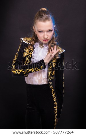 Portrait of teen girl in a suit of black bullfighter dancing and posing on a dark background in the studio