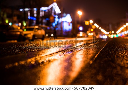 Rainy night in the big city, parked the car on the road. Close up view from the level of the double solid line