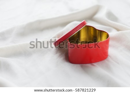 Old box in heart shape on white background, on white cloth, in box red sweet jelly beans, Valentine's day, women's day, gifts.
