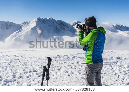 Tourist does photo camera to the mountain landscape in winter.
