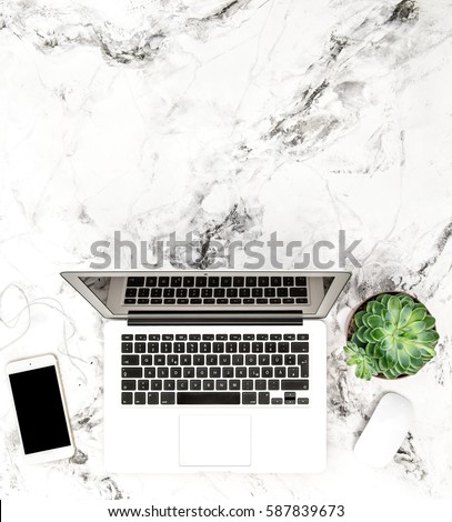 Laptop, phone, succulent plants on marble background. Working desk. Flat lay