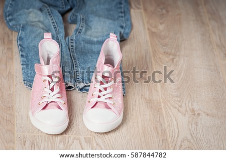 a pink shiny shoes and blue jeans  for girls isolated on a wooden background