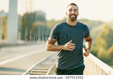 Handsome young man running across the bridge. 