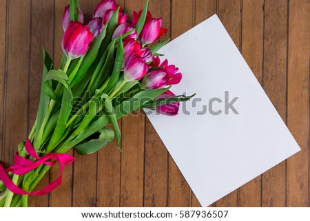 Row of tulips on wooden background with space for message. Mother's Day background. Top view