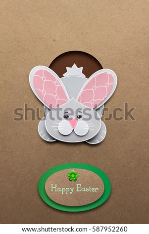 Creative easter concept photo of a rabbit in a hole made of paper on brown background.