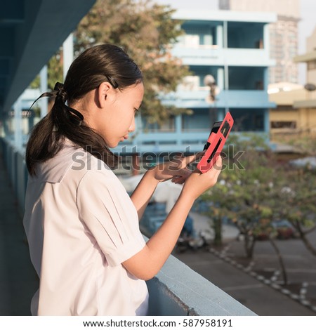Asain high school girl play smartphone in morniing time