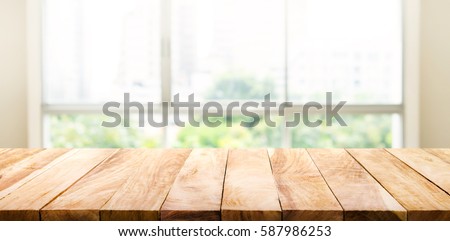 Wood table top on blur of window glass and abstract green from garden with city view in the morning background. For montage product display 