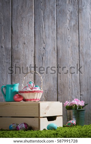 Easter eggs painted on a wooden background of boards on green grass.