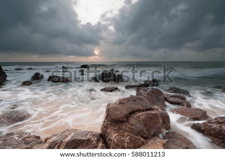 Blurry effect on wave on stone beach in Malaysia due to long exposure of photography technique.