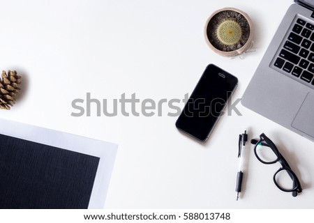 White office desk table with laptop, file, pinecones, smartphone, and cactus. Top view with copy space, flat lay.