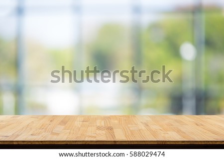 wooden table in front of abstract Blur white green background from office window