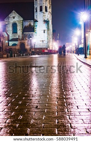 Night street in the Krakow, Poland. Colorful night illumination reflecting in the wet stone pavement of the old town. Beautiful background photo.