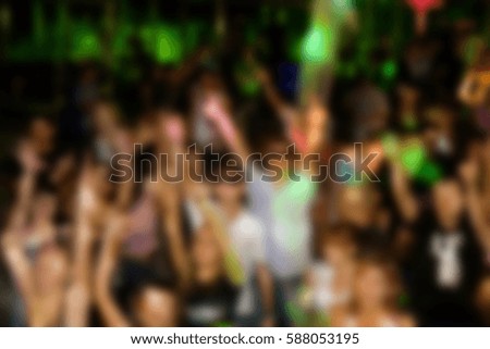 Blurry background of people party in the nightclub.Night club audience dance to the music.Adult night life entertainment show,crowded dancefloor have fun at dj concert.Music festival poster background