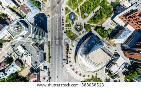 Aerial city view with crossroads, roads, houses, buildings, parks and parking lots. Copter drone helicopter shot. Panoramic wide angle image.