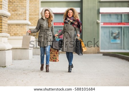 Two friends walking on the street and smiling