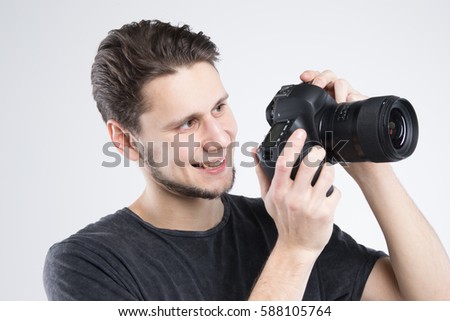 Young man holding camera in black shirt isolated