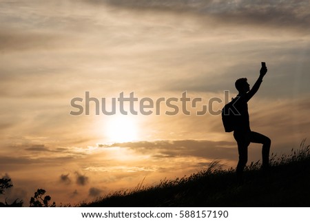 silhouette of a man raised his hand up with a phone