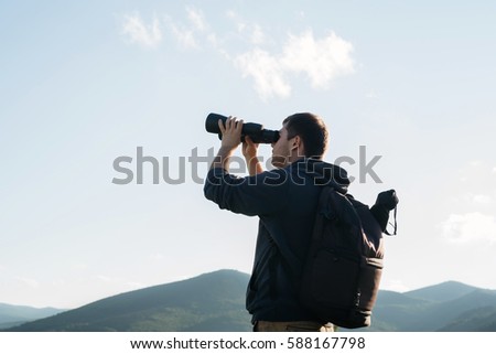man look in binocular at landscape