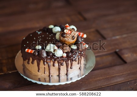 homemade cake decorated with sweets, cupcakes and waffles.