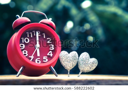 time for love, alarm clock and glitter hearts on wooden and nature background