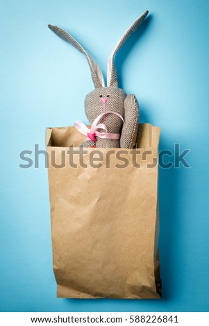 Easter bunny in a paper bag. Rabbit. Blue background. Easter ideas. Easter eggs. Space for text.