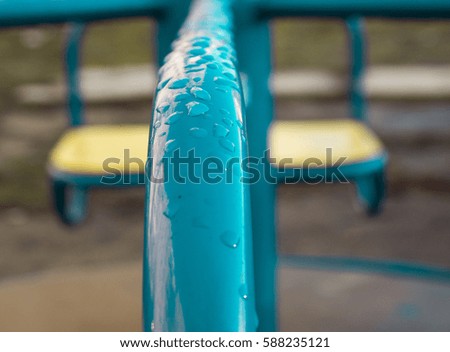 Raindrops on a blue metallic infant swings closeup