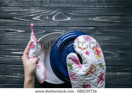Set of kitchen textile and a pot  female's hands  on dark grey wooden background