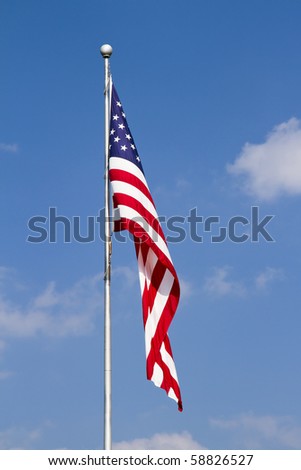 US Flag  waving on Pole against a blue, cloud-draped sky. Vertical.