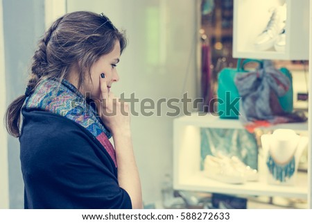 Young and attractive lady window shopping. Deciding what to buy.