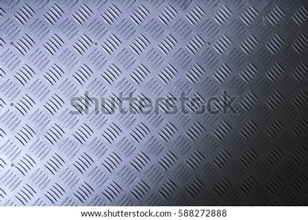 Industrial wallpaper of functional anti-slip metal tread plate in grey silver color and rough raised surface pattern. Creative lighting macro photography of construction for catwalks, stairs, walkway.