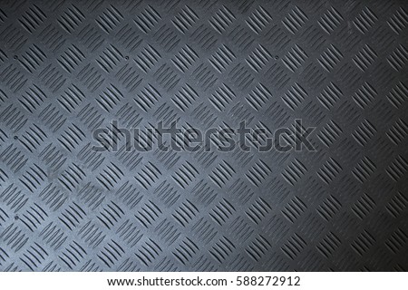 Industrial wallpaper of functional anti-slip metal tread plate in grey silver color and rough raised surface pattern. Creative lighting macro photography of construction for catwalks, stairs, walkway. Royalty-Free Stock Photo #588272912