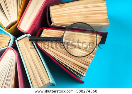 Top view of colorful hardback books in a circle and magnifying glass. free copy space. Back to school copy space. Education background.