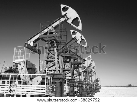 Oil pump jack on a sand. Black and white photo