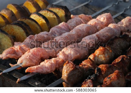 raw and roasted meat with spices and potatoes on skewers