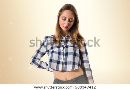 Blonde teen girl with back pain on ocher background