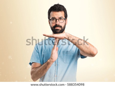 Handsome man making time out gesture on ocher background