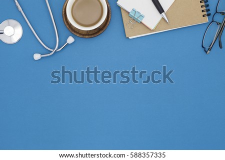 Stethoscope with notebook ,pencil, white paper ,coffee cup,glasses on blue background,Medical background concept