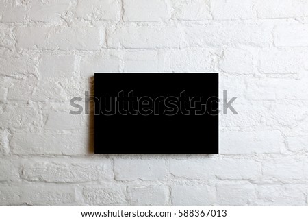 Black blank poster in a white brick wall. Template Mock up for your content.