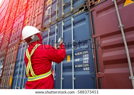 Foreman control loading containers box from Cargo freight ship,Freight shipping containers at the docks,Large container shipping at shipping yard main transportation of cargo container shipping. Royalty-Free Stock Photo #588373451