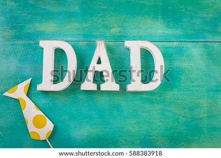 White letters DAD on a painted wood background.