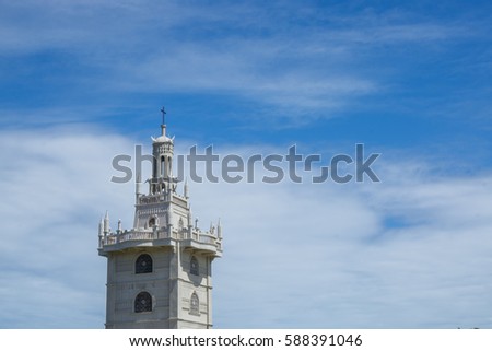 The cross on top of a tower at the Simala-Lindogon Church Shrine in Sibonga, Cebu, Philippines with a cloudy, blue sky background.