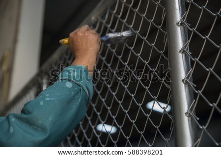 Closeup of hand's workers,painted grid iron fence.