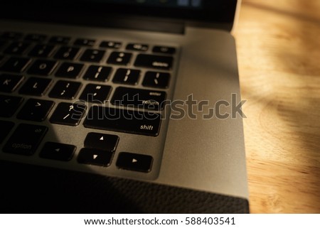 Laptop computer keyboard on sunshine on wooden background