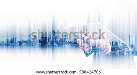 Double exposure businessman working on digital tablet with modern city, concepts of technology business development