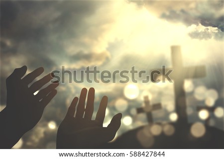 Picture of hands praying to the GOD with three crosses symbol and bright sunbeam on the sky
