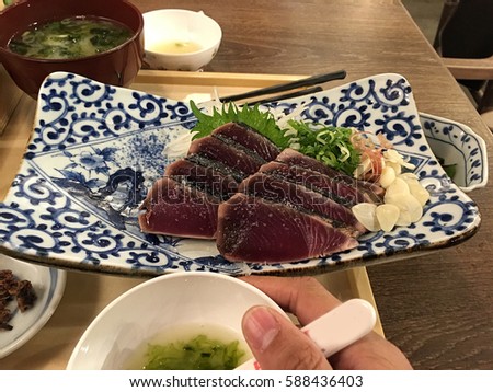 Katsuo no tataki, lightly broiled, sliced bonito (skipjack tuna). Served alongside spring onions, ginger and garlic and seasoned with salt or soya sauce with vinegar and citrus. Royalty-Free Stock Photo #588436403