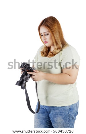 Image of female photographer holding a digital camera while looking at a photo on the camera screen, isolated on white background