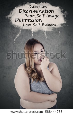 Picture of obese woman looks depressed, thinking her problems while biting nails