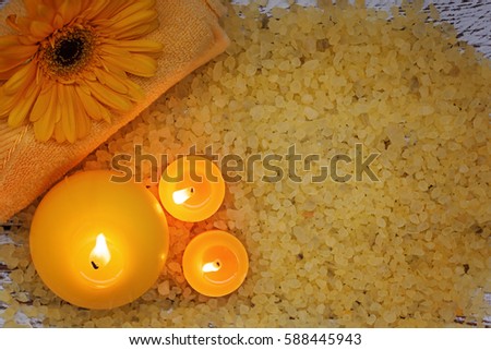 Spa yellow products setting. Sea salt ,towel and candles on dark wooden background. Top view.