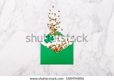St.Patrick 's Day concept. Empty card with green envelope and gold confett and clover leafi. Mockup template. View from above